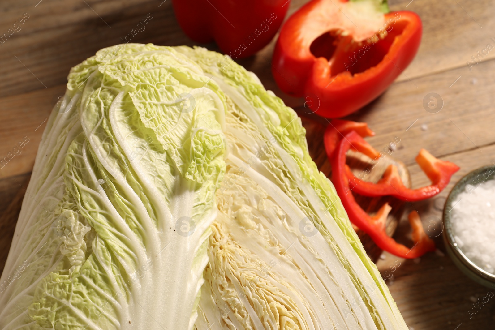 Photo of Fresh Chinese cabbages, bell peppers and salt on wooden table, closeup