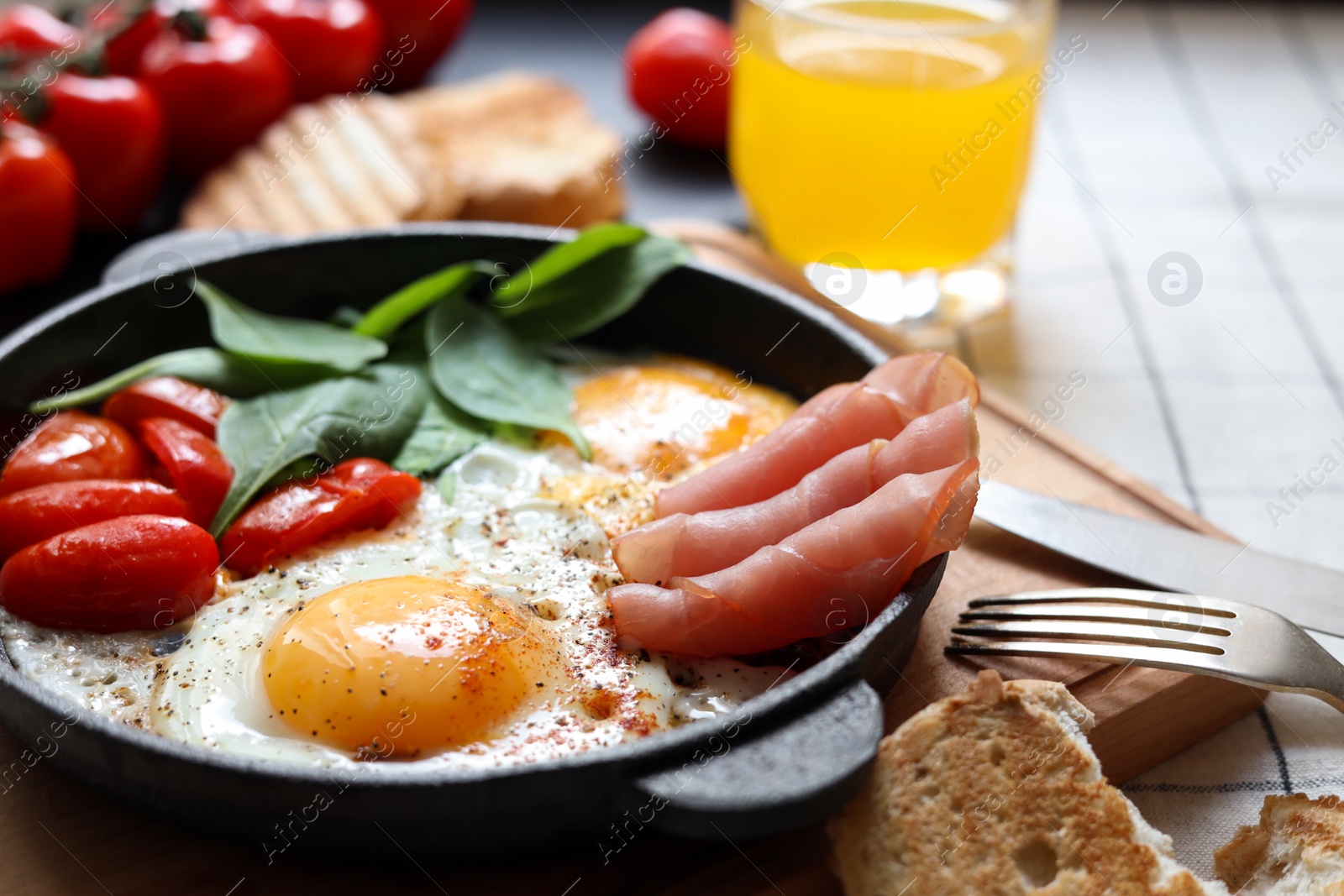 Photo of Delicious fried eggs with spinach, tomatoes and ham served on table, closeup