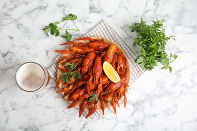 Photo of Delicious boiled crayfishes on white marble table, flat lay