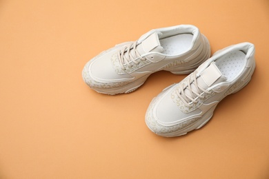 Image of Stylish white shoes on pale orange background