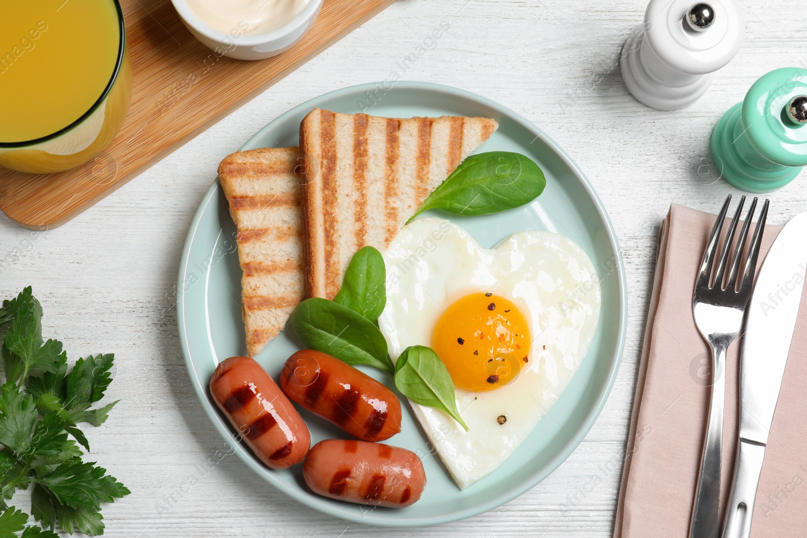 Photo of Tasty breakfast with heart shaped fried egg served on white wooden table, flat lay