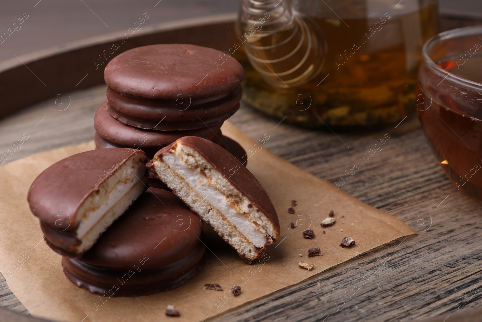 Photo of Tasty choco pies and tea on wooden tray, closeup view