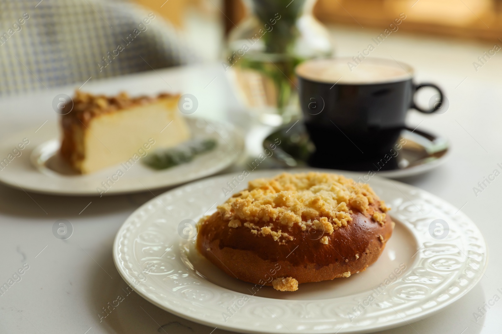 Photo of Fresh bun, tasty cheesecake and cup of coffee on table indoors