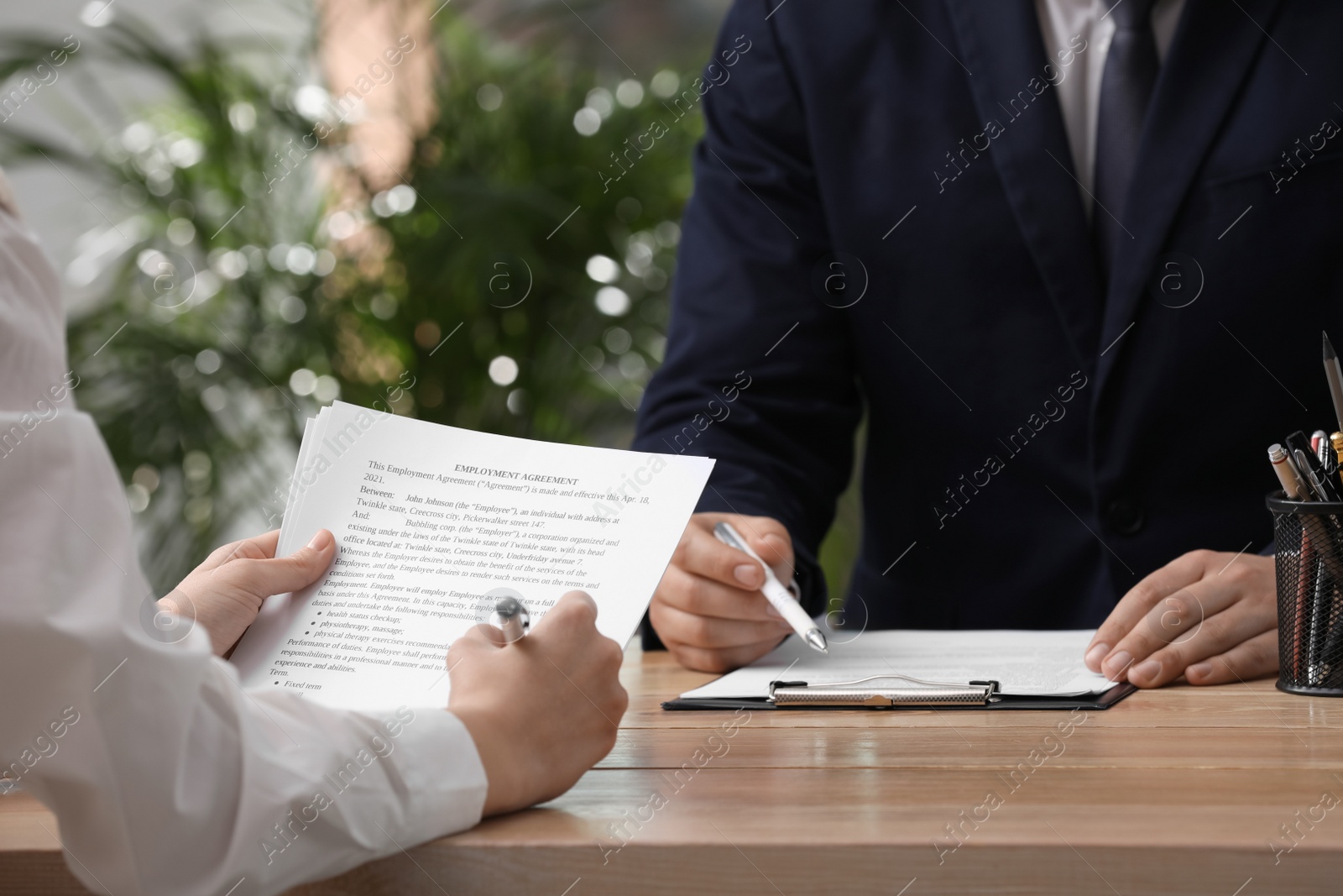 Photo of Woman signing employment agreement at table in office, closeup. Work contract