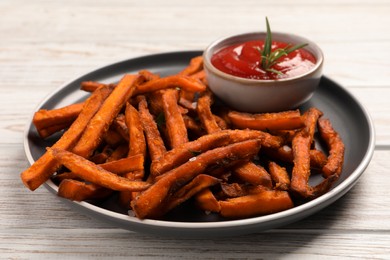 Delicious sweet potato fries served with sauce on white wooden table, closeup