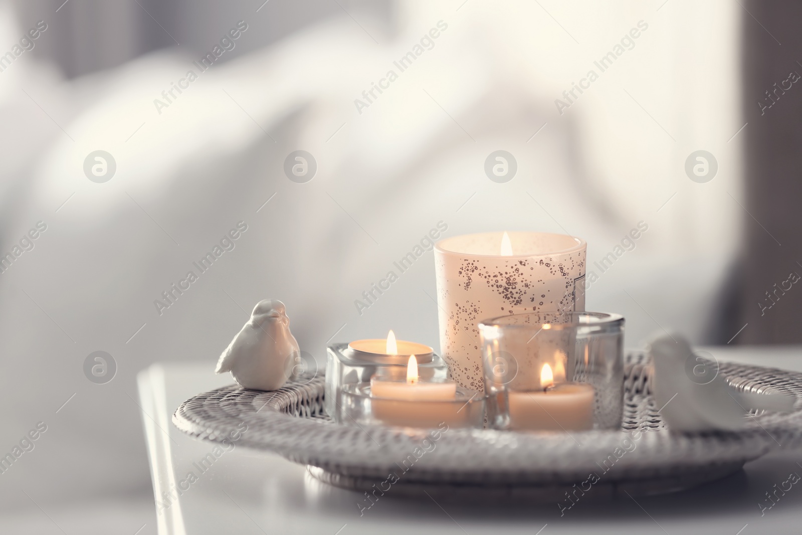 Photo of Beautiful burning candles on tray against light background