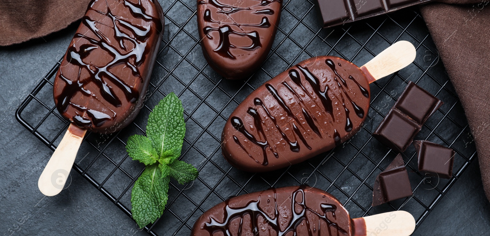 Image of Delicious glazed ice cream bars, chocolate and mint on black table, flat lay. Banner design