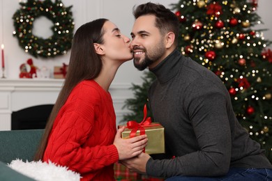 Photo of Beautiful young woman thanking her boyfriend for Christmas gift at home