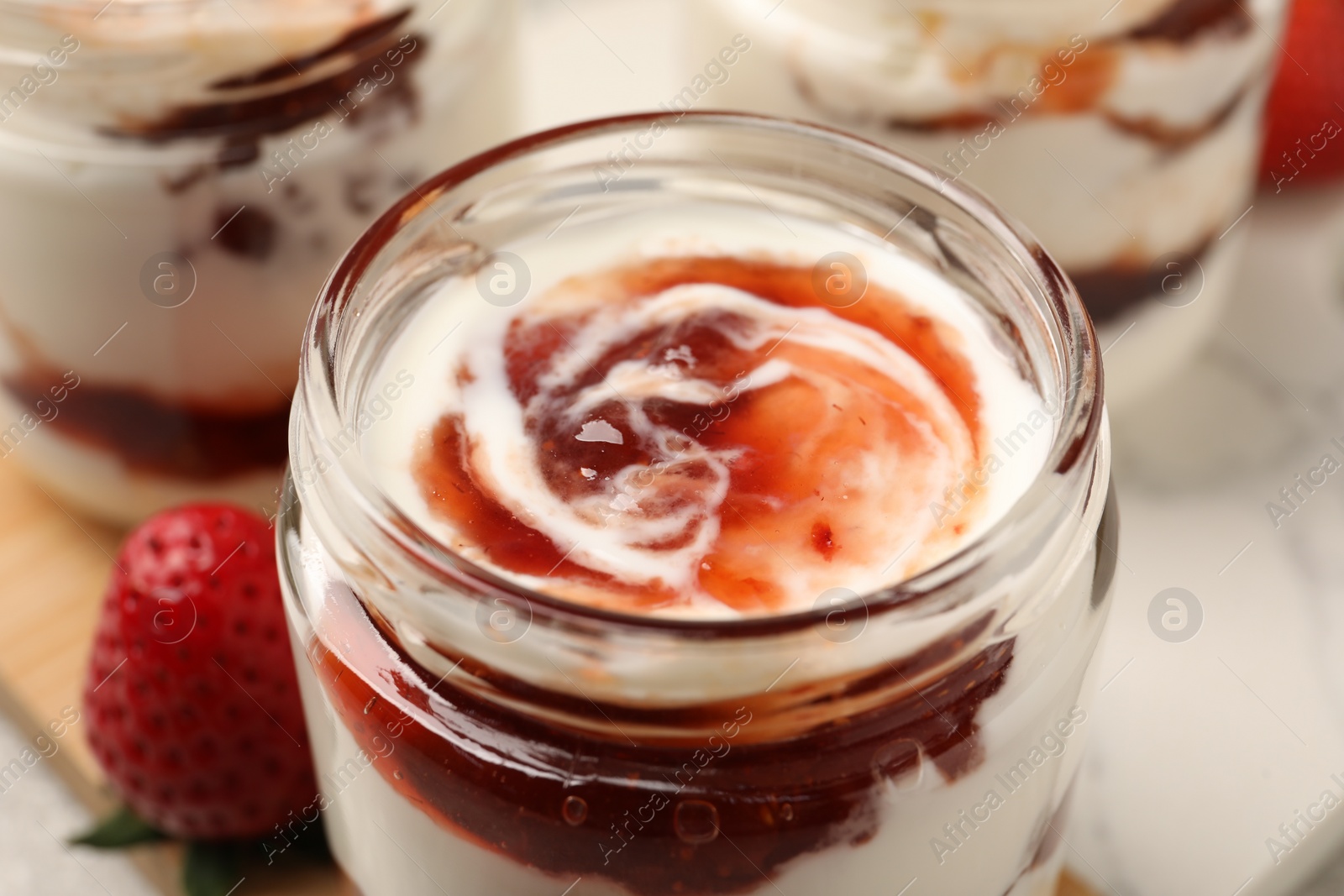 Photo of Tasty yoghurt with jam and strawberry on table, closeup