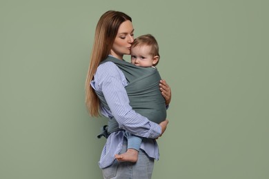 Photo of Mother holding her child in baby wrap on olive background