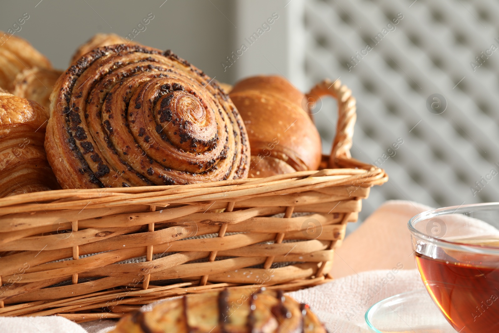 Photo of Different tasty freshly baked pastries in wicker basket on table, closeup. Space for text