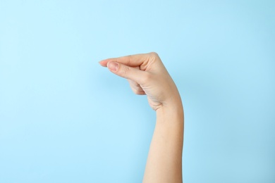 Woman showing G letter on color background, closeup. Sign language