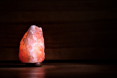 Photo of Himalayan salt lamp glowing on dark background with space for text