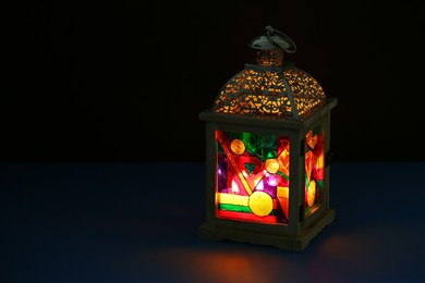 Decorative Arabic lantern on table against dark background. Space for text