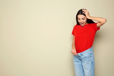 Photo of Slim woman in oversized jeans on color background, space for text. Weight loss
