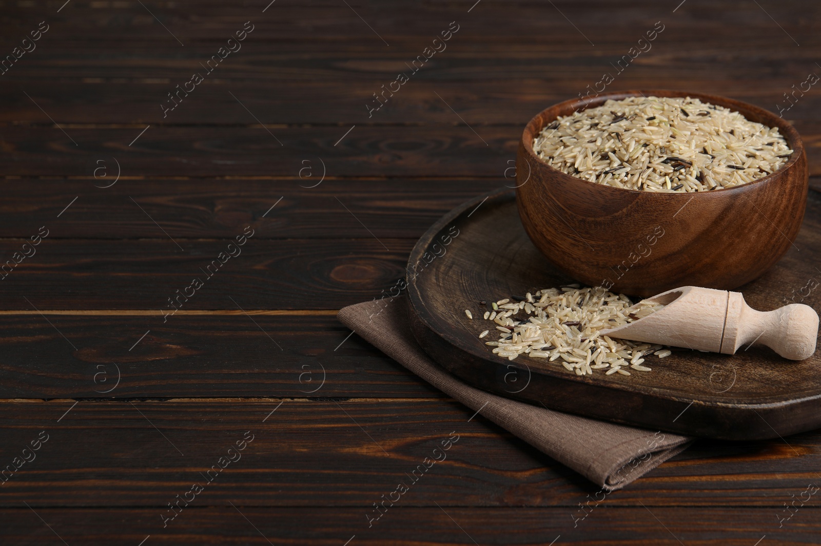 Photo of Raw unpolished rice on wooden table. Space for text