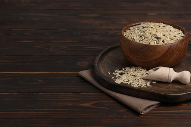 Photo of Raw unpolished rice on wooden table. Space for text