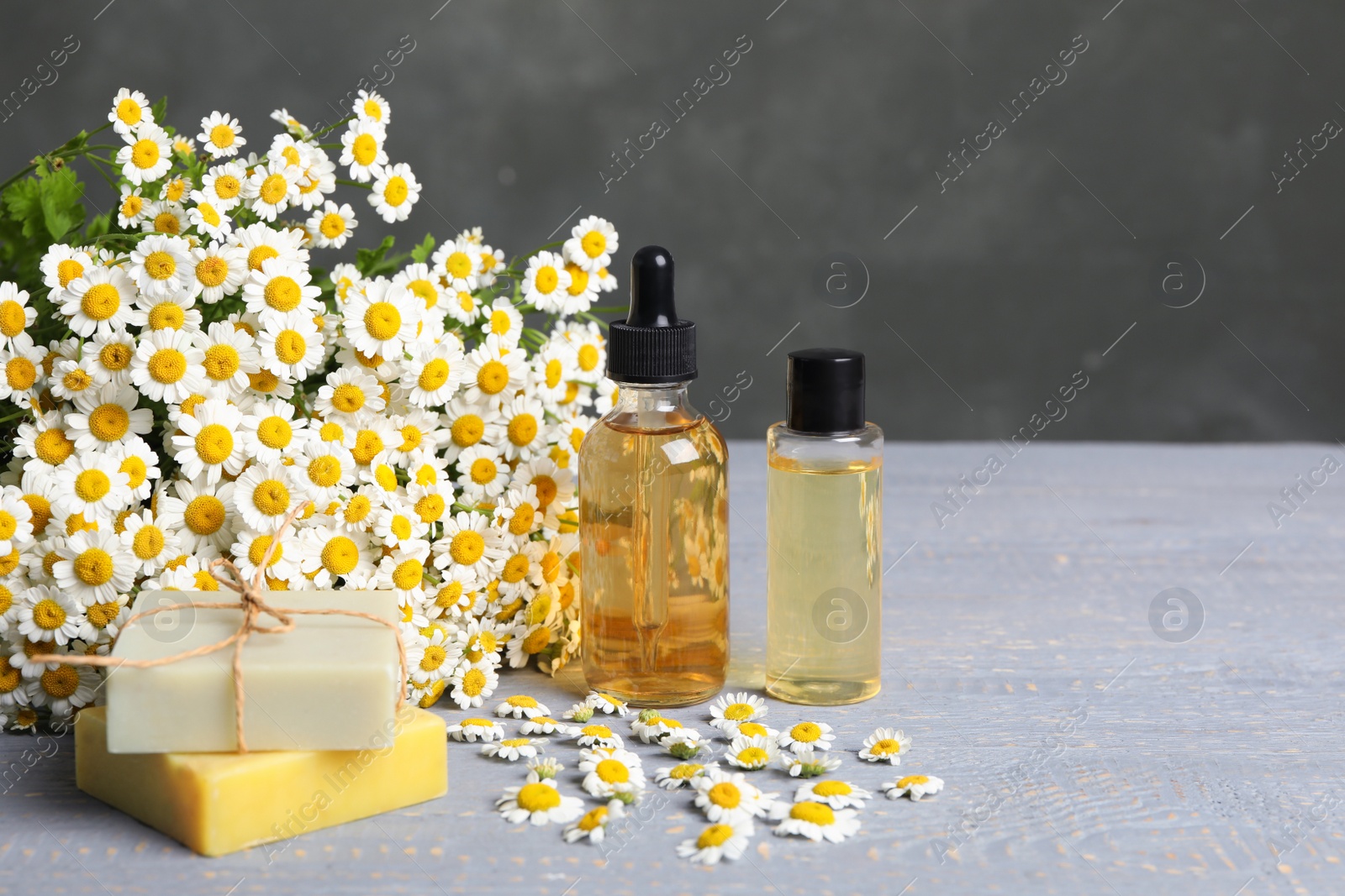 Photo of Composition with chamomile flowers and cosmetic products on wooden table
