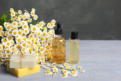 Photo of Composition with chamomile flowers and cosmetic products on wooden table