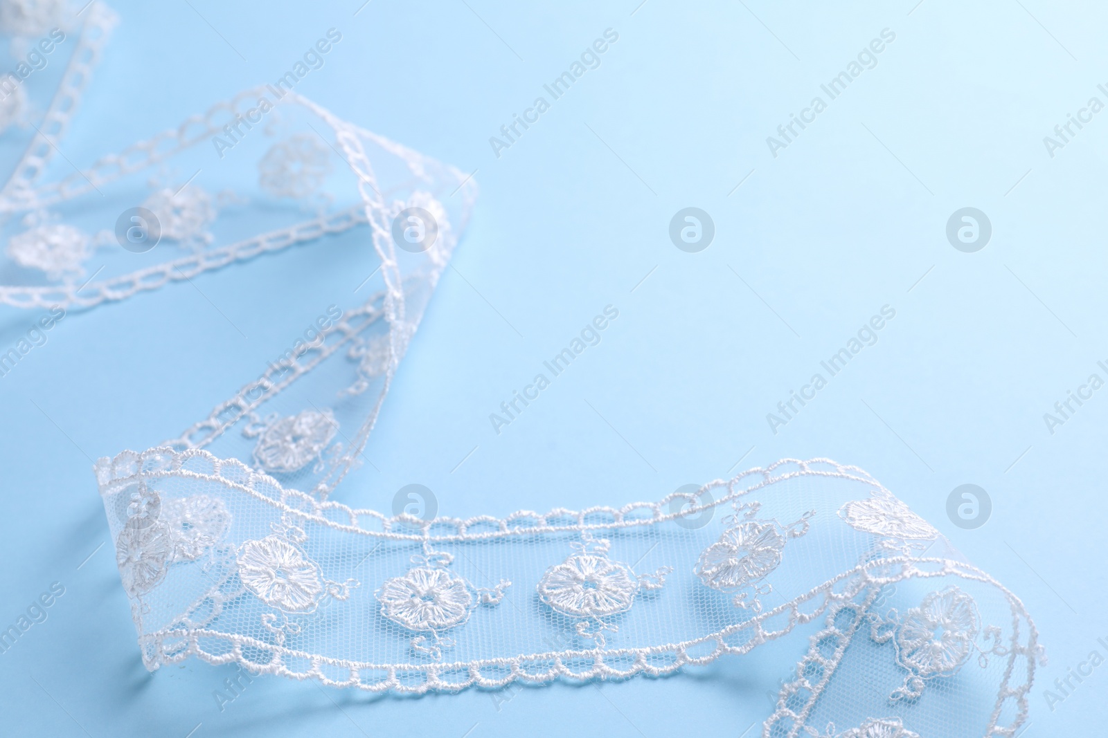 Photo of White lace on light blue background, closeup