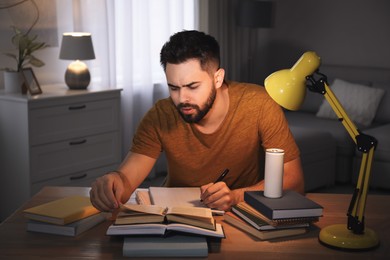 Photo of Tired young man with energy drink studying at home