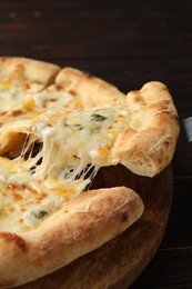 Taking piece of delicious cheese pizza at wooden table, closeup