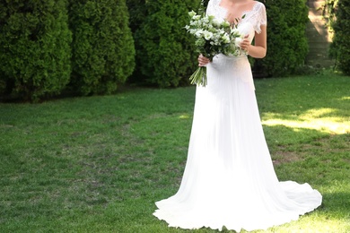 Bride in beautiful wedding dress with bouquet outdoors, closeup. Space for text