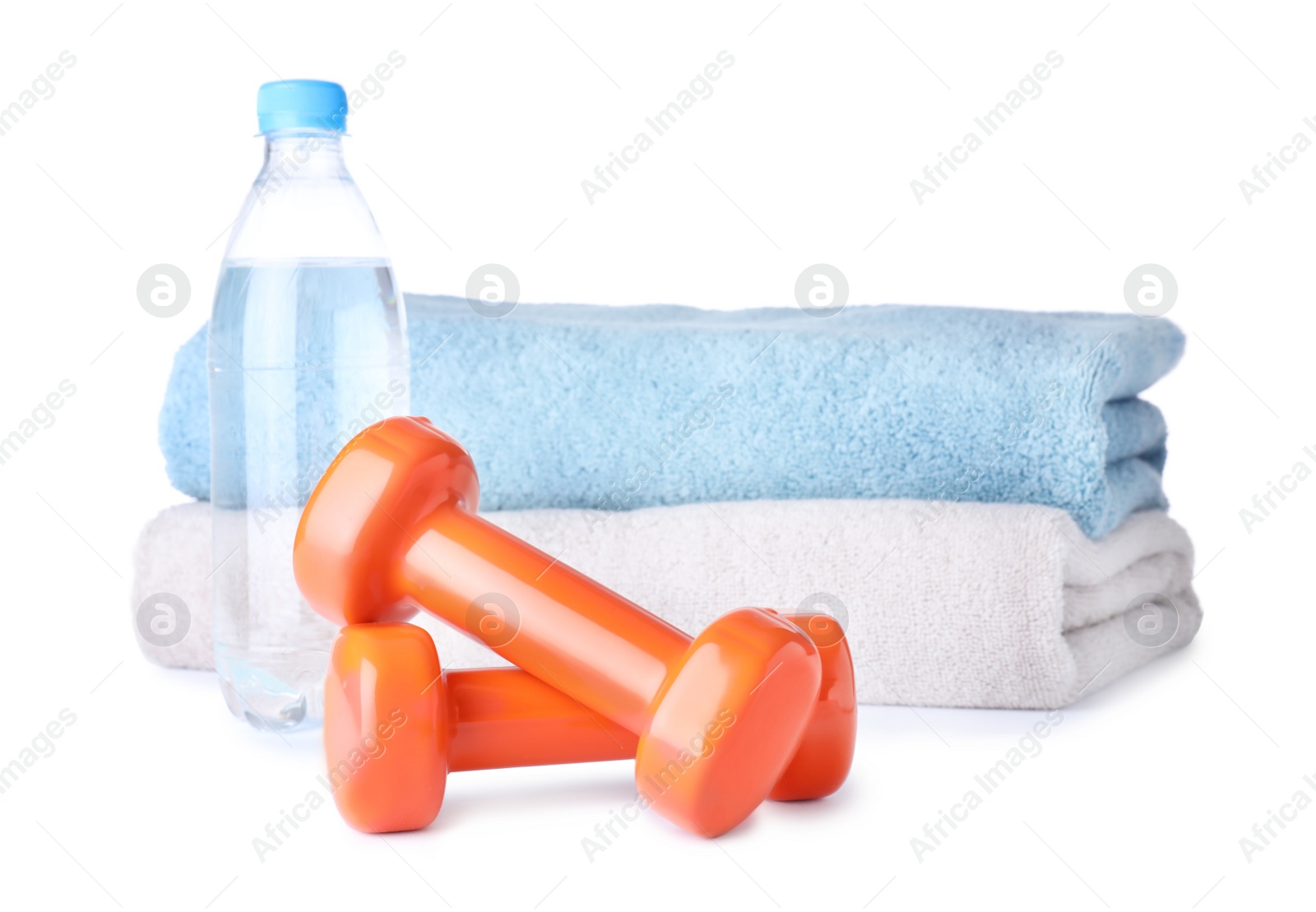 Photo of Stylish dumbbells, bottle of water and towels on white background. Home fitness