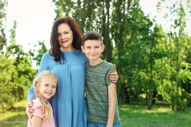 Female pensioner with grandchildren in park. Space for text