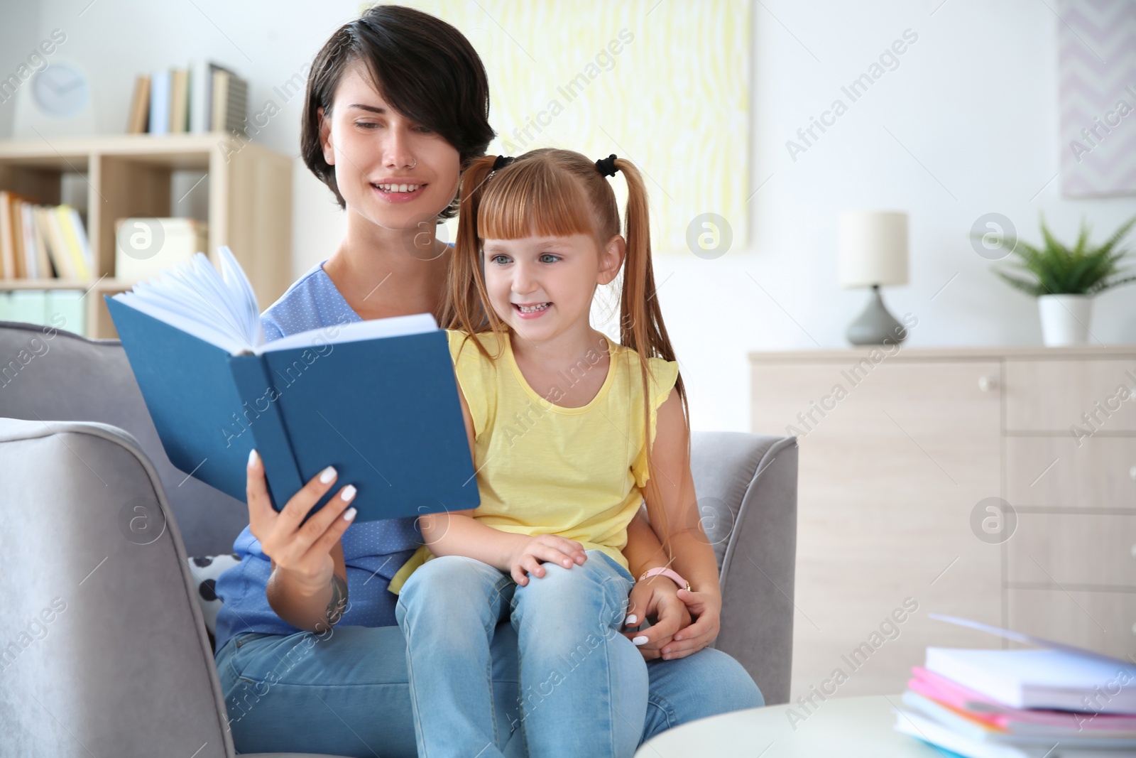 Photo of Young woman helping her child with homework at home. Elementary school