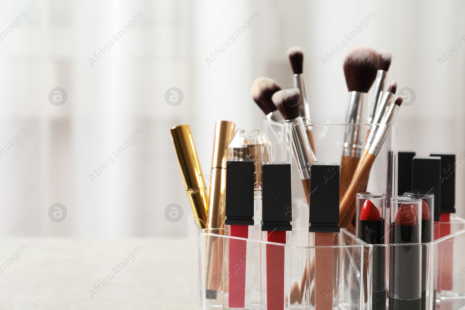 Photo of Lipstick holder with different makeup products on table indoors, closeup. Space for text
