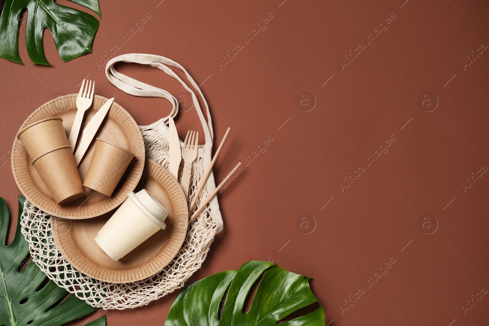 Photo of Flat lay composition with disposable tableware on brown background. Space for text