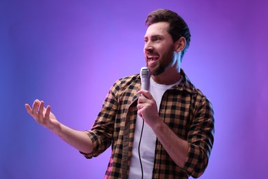 Photo of Handsome man with microphone singing in neon lights