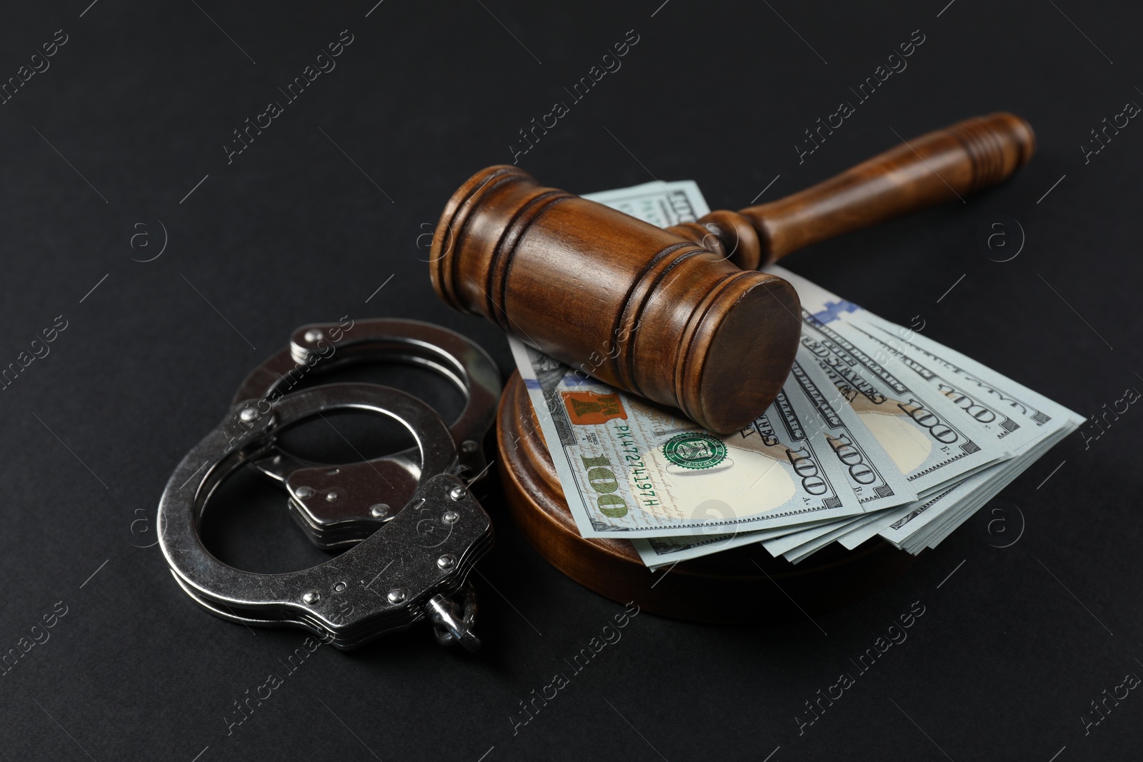Photo of Judge's gavel, money and handcuffs on black background