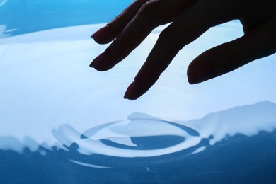 Woman touching clear water, closeup. Making ripples