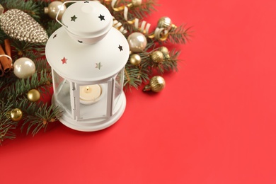 Photo of Christmas lantern with burning candle and festive decor on red background. Space for text