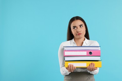 Photo of Disappointed woman with folders on light blue background, space for text