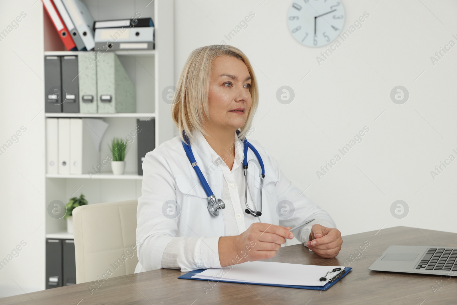 Photo of Doctor sitting at wooden table in clinic