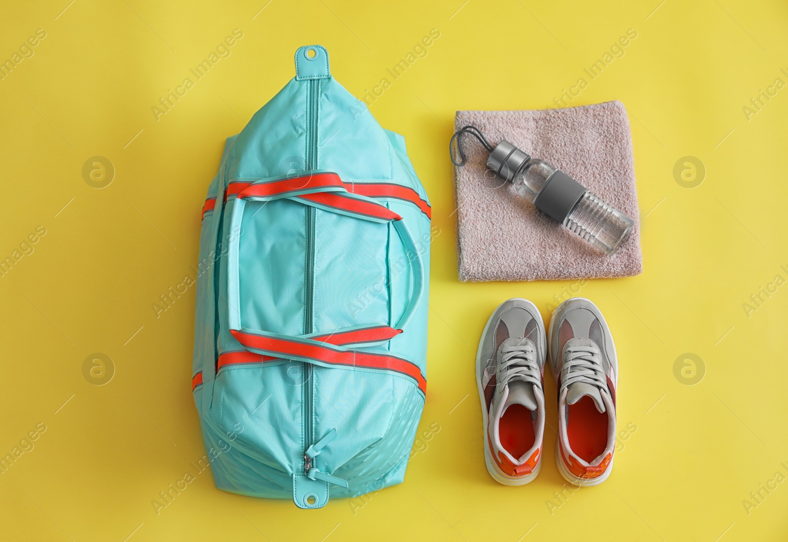 Photo of Gym bag and sports equipment on yellow background, flat lay