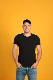 Photo of Happy man in black cap and tshirt on yellow background. Mockup for design