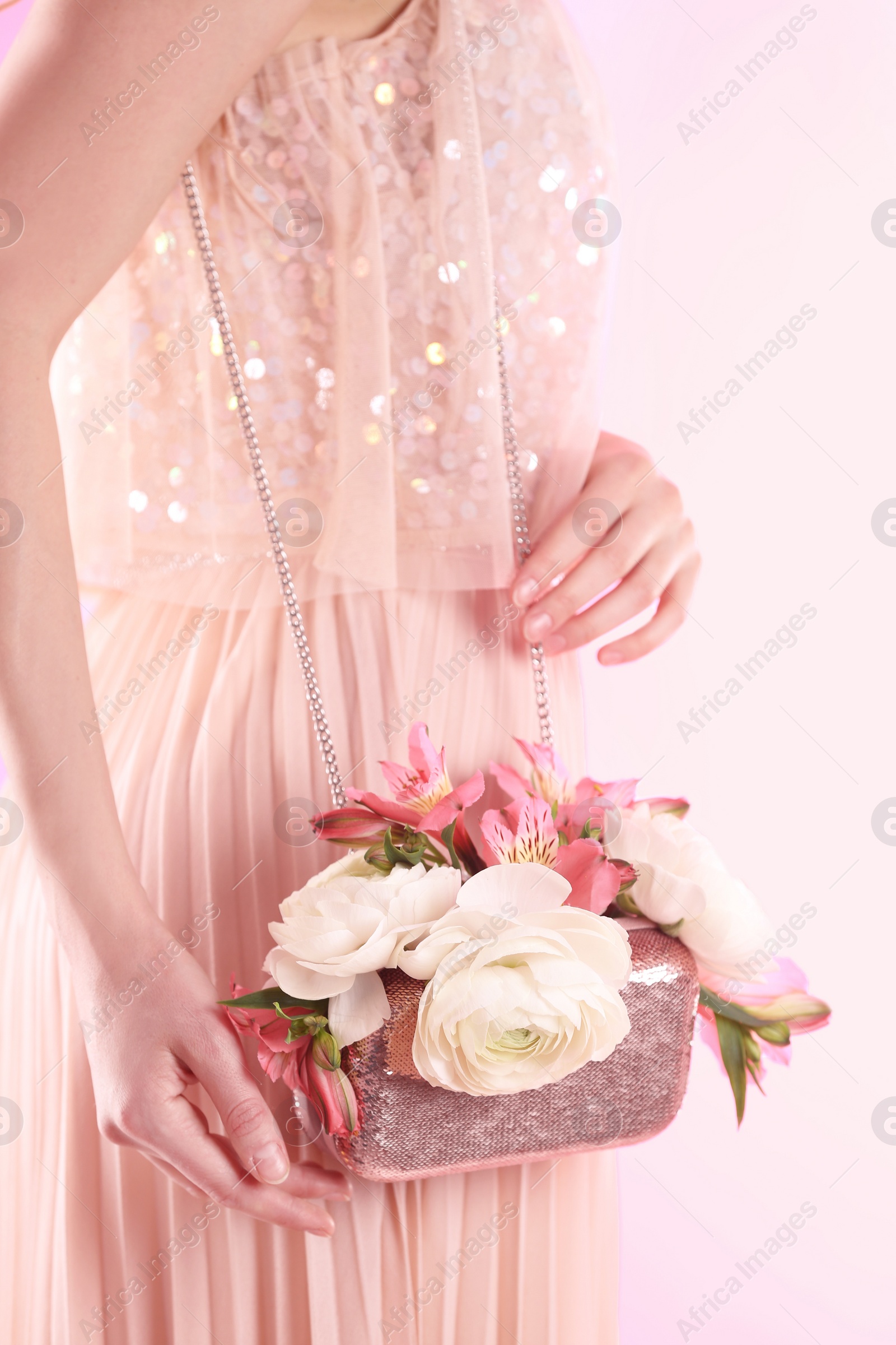 Photo of Woman holding elegant handbag with spring flowers on pink background, closeup