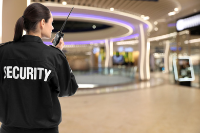 Security guard using portable radio transmitter in shopping mall, space for text