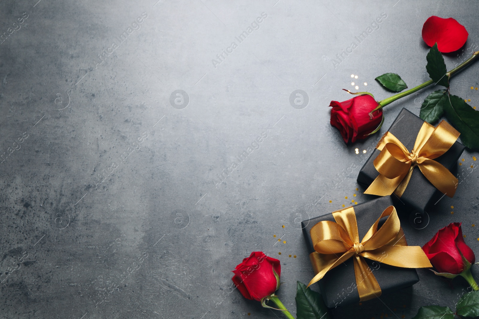 Photo of Two black gift boxes and beautiful roses on dark background, flat lay. Space for text