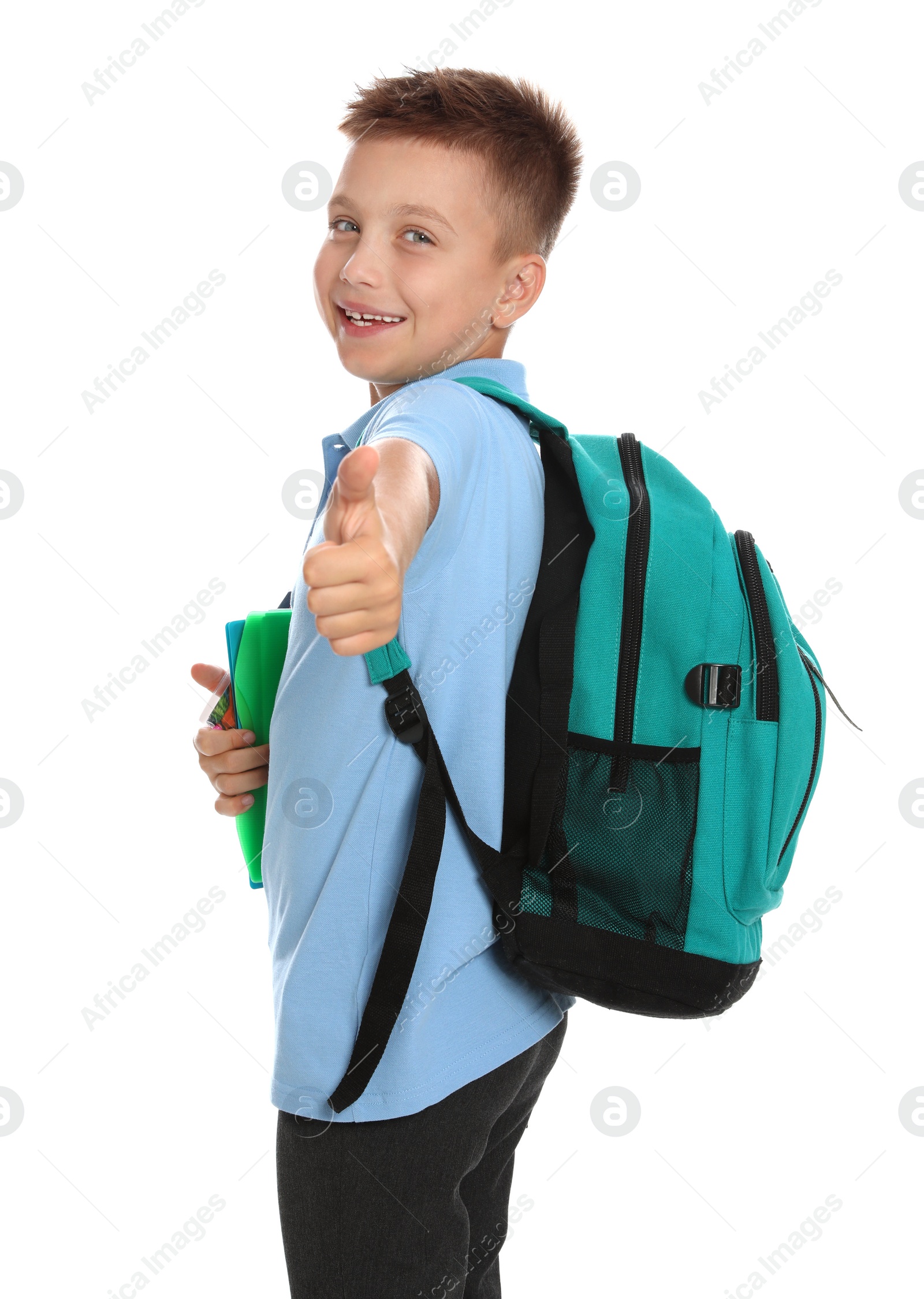 Photo of Cute little boy in school uniform with backpack and stationery showing thumbs-up on white background