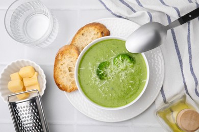 Photo of Delicious broccoli cream soup with cheese served on white tiled table, flat lay