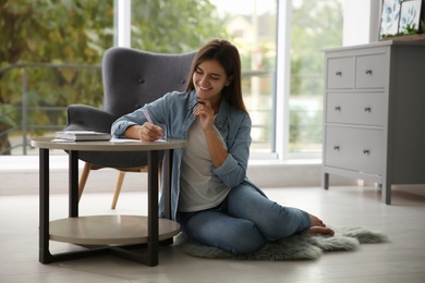 Photo of Woman writing paper letter at table indoors