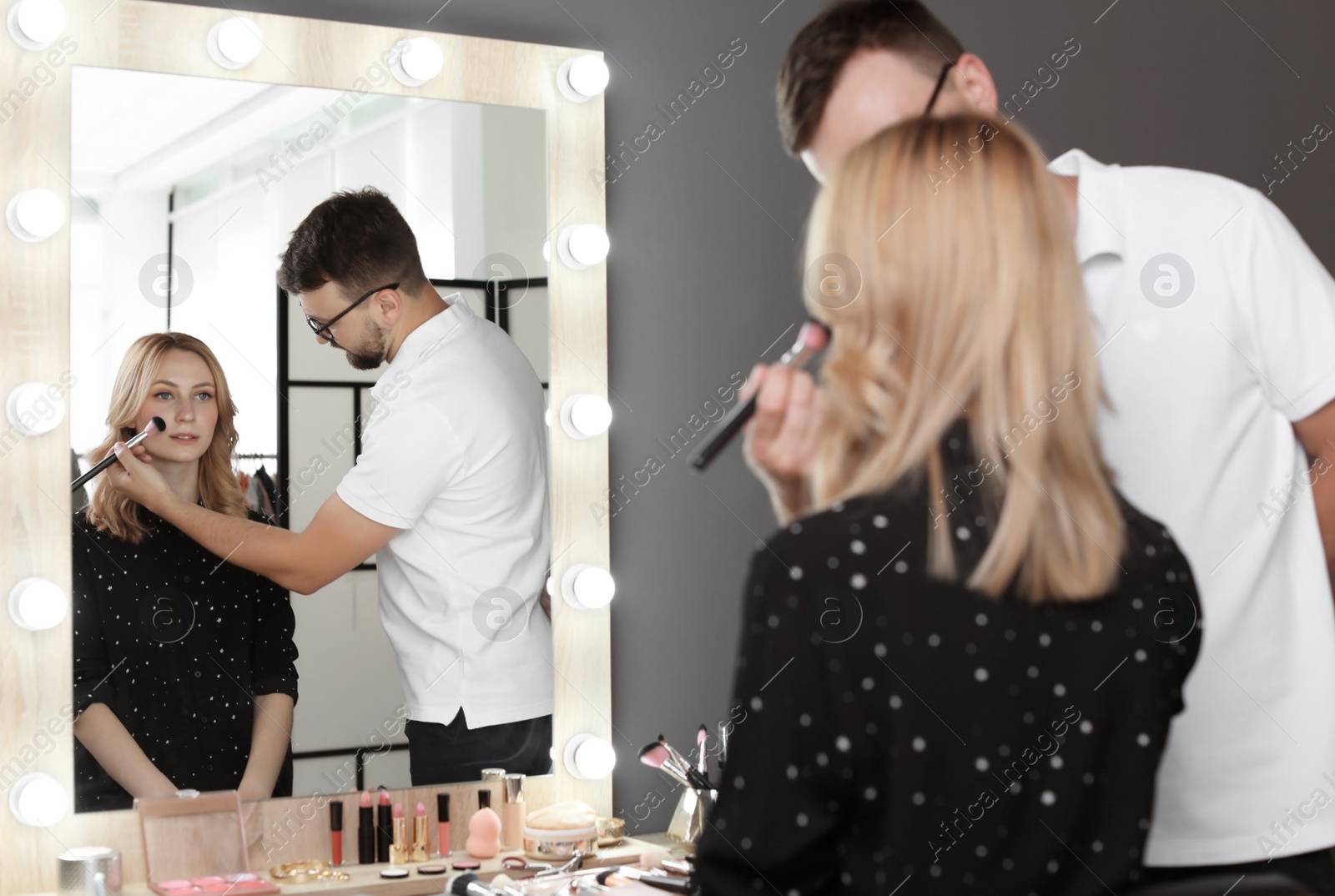 Photo of Professional makeup artist working with client in dressing room