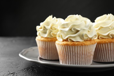 Tasty cupcakes with vanilla cream on black table, closeup