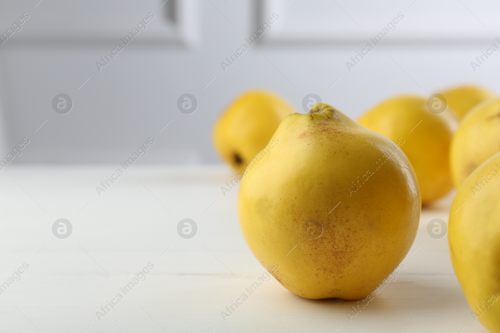 Photo of Tasty ripe quinces on white wooden table, closeup. Space for text