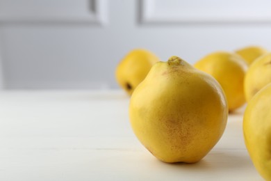 Photo of Tasty ripe quinces on white wooden table, closeup. Space for text